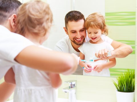 Happy Family Father and Child Girl Brushing Her Teeth In Bathroom